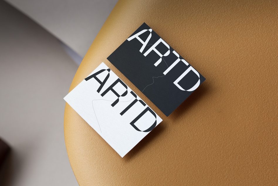 Business card mockup with artistic font design on tan leather surface, showcasing modern branding and typography for designers.